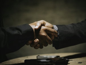 two people shaking hands over a wooden table